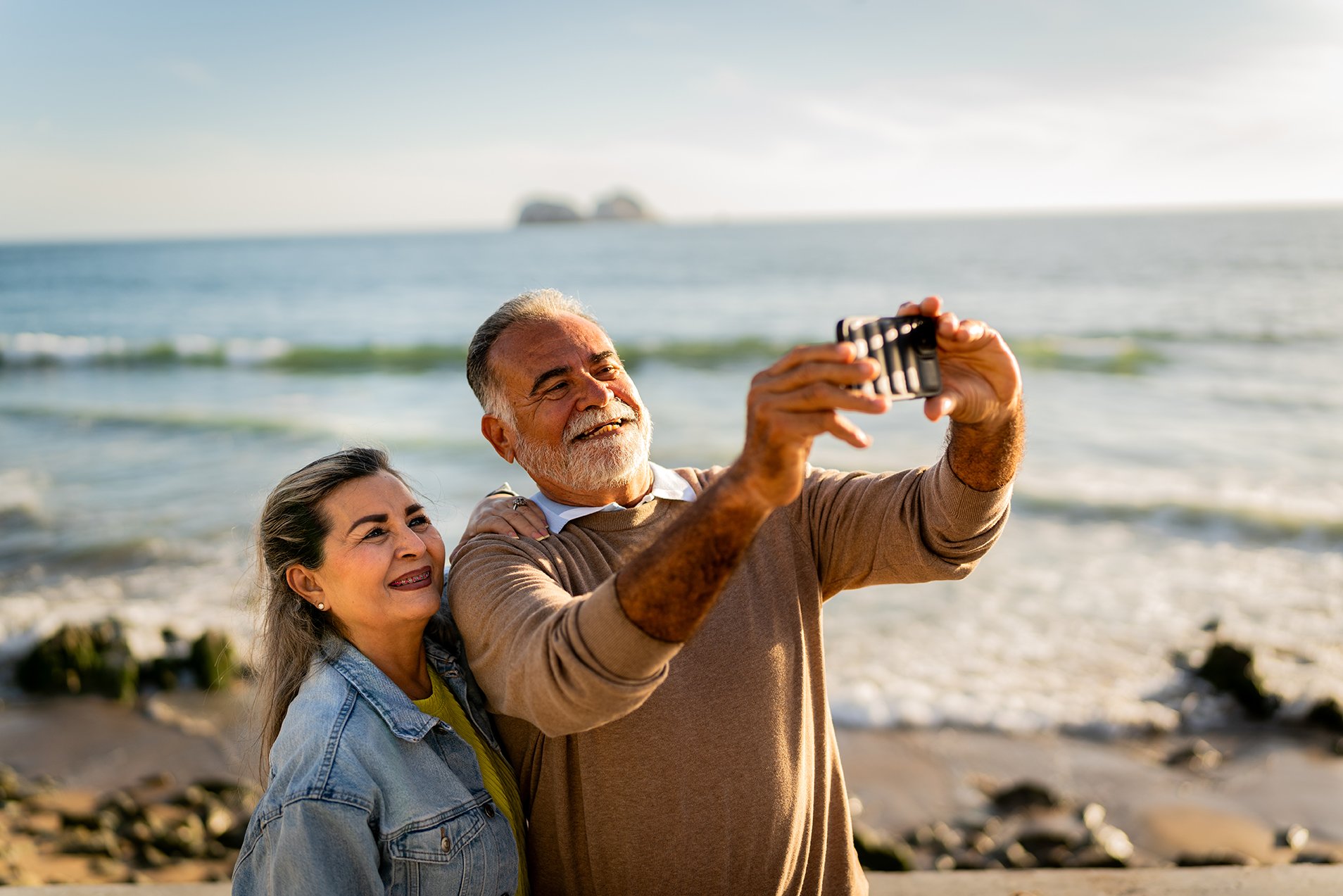 Senior couple taking a selfie on the beach