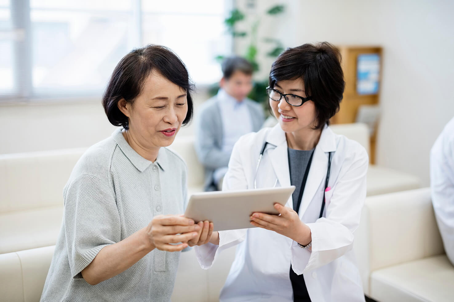 Female doctor showing digital tablet to patient in hospital.