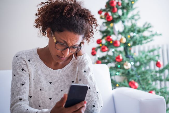 Troubled woman looking at phone at Christmas