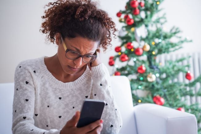 Troubled woman looking at phone at Christmas