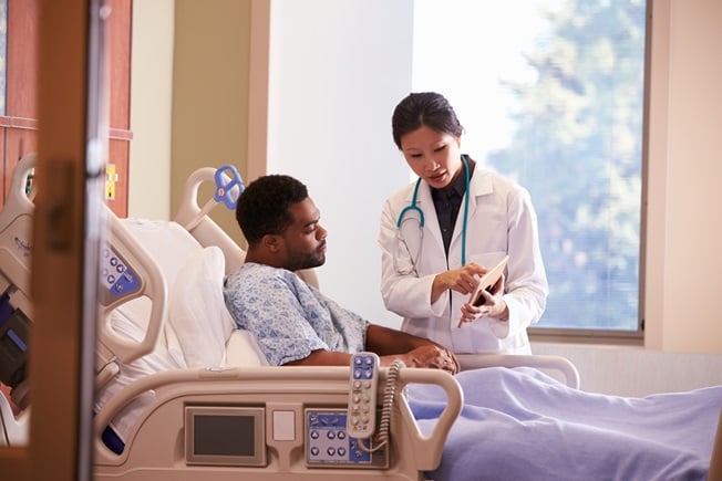 Adult male in hospital bed with doctor