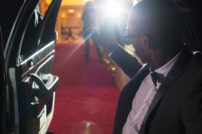 A male celebrity steps out of a limo to flashbulbs