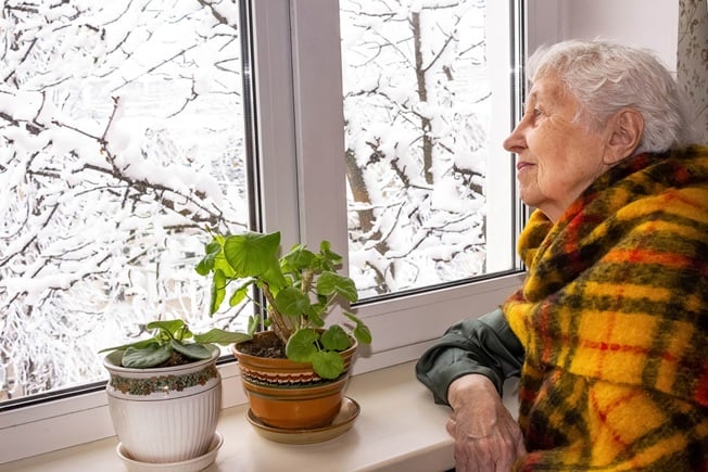 Senior woman looking out window at snow