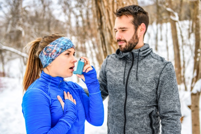 Couple running with wife using asthma inhaler