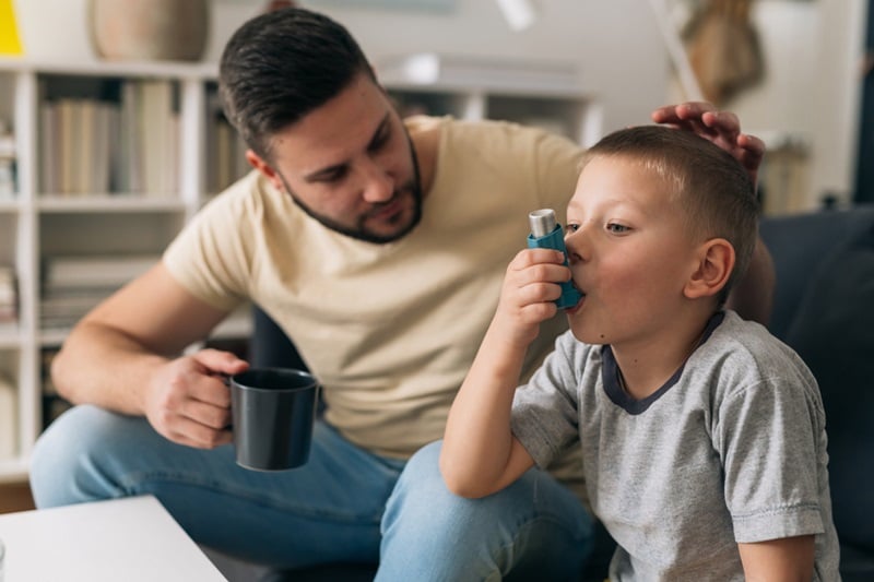 Father and son who is using an asthma inhaler