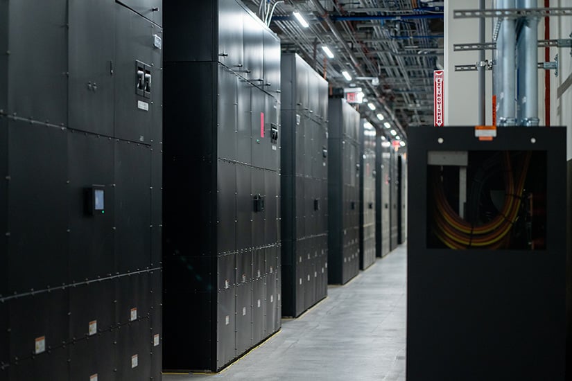 A secure data centre with tall black cabinets neatly lined up illustrates the capability to decommission large volumes of data and assets.