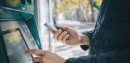 individual using smartphone while accessing atm