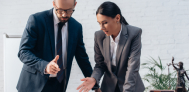 pair of business people gesturing towards papers and desk