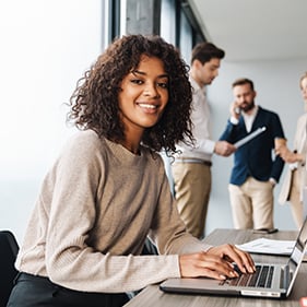 Smiling employee using laptop in modern office space