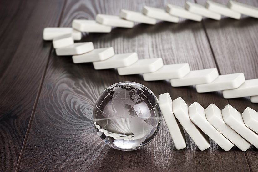 A set of dominoes leaning against a marble-sized earth represents how efficient IT asset management drives the progress of the enterprise forward.
