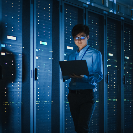 an employee working on server in dark, illuminated by laptop light
