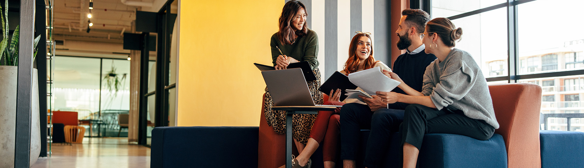 four employees in contemporary office sitting on comfortable couch