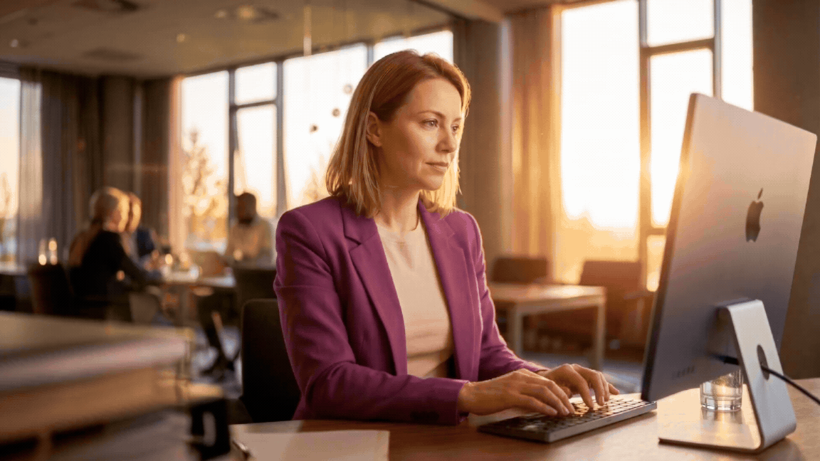 Information supercycle - woman in a purple blazer typing in an office