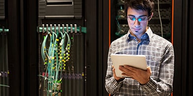 Man in a shirt in data workplace looking at the white tablet