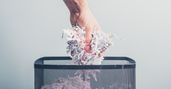 Protect your small business with these data security tips | hand picking up shredded paper