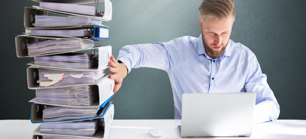 Man at laptop with stacks of binders