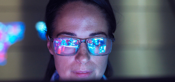 Engineer examining AI technology with reflection on eyeglasses