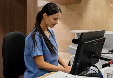 A woman in a blue scrubs using a computer