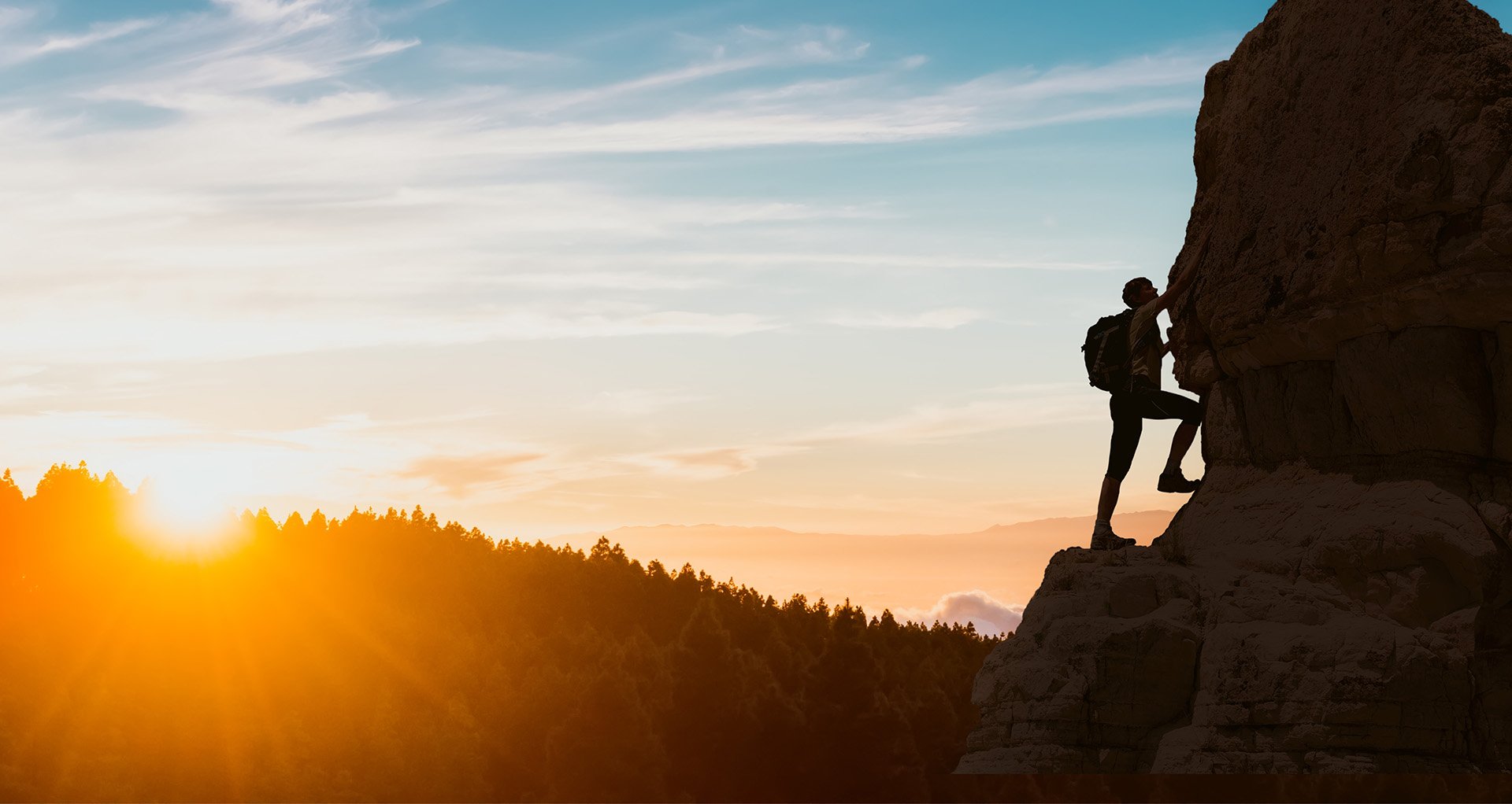 a silhouette of a man climbing a mountain