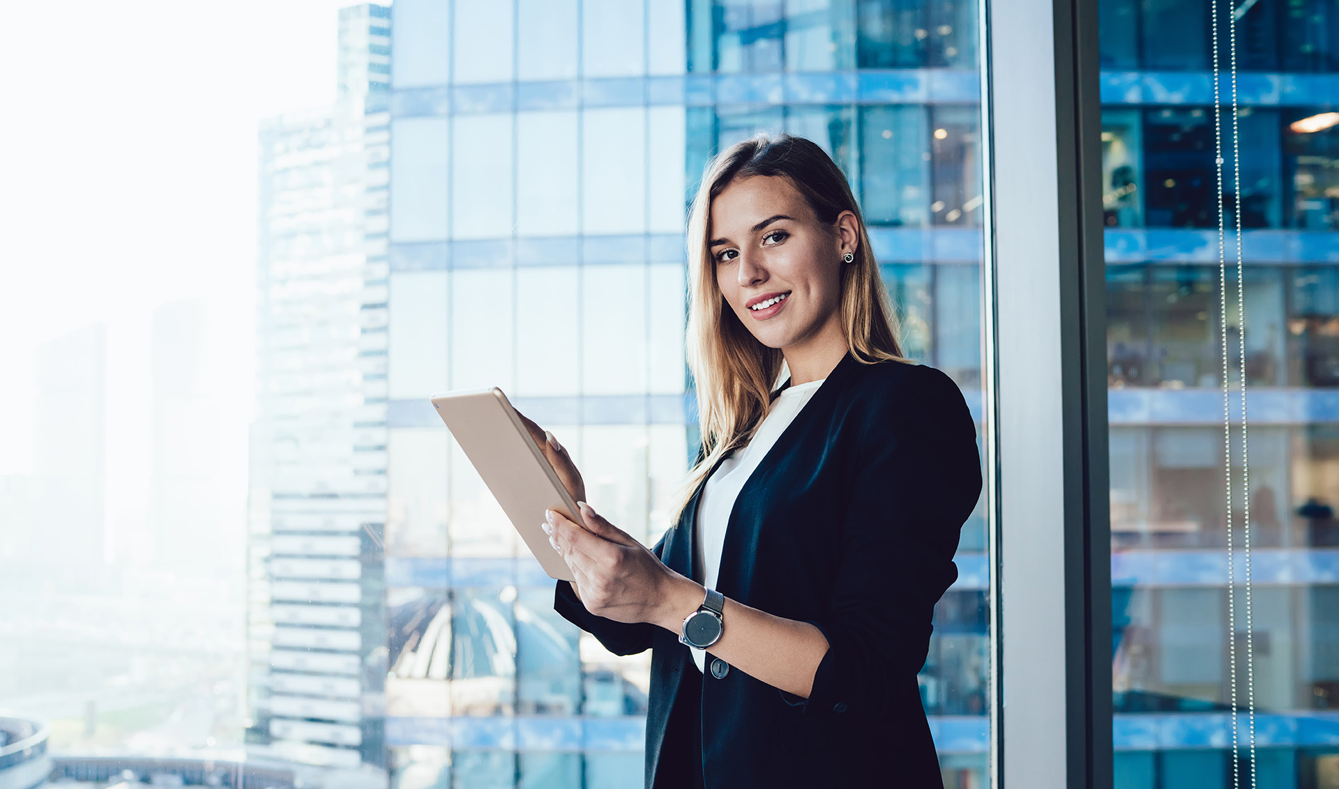confident businesswoman holding tablet in modern office space