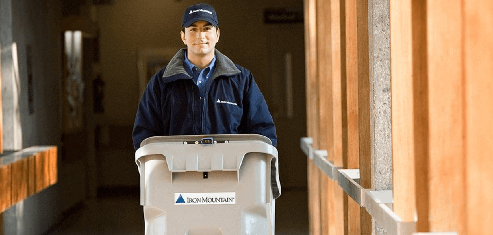 IM employee wheeling paper shredding bin offsite