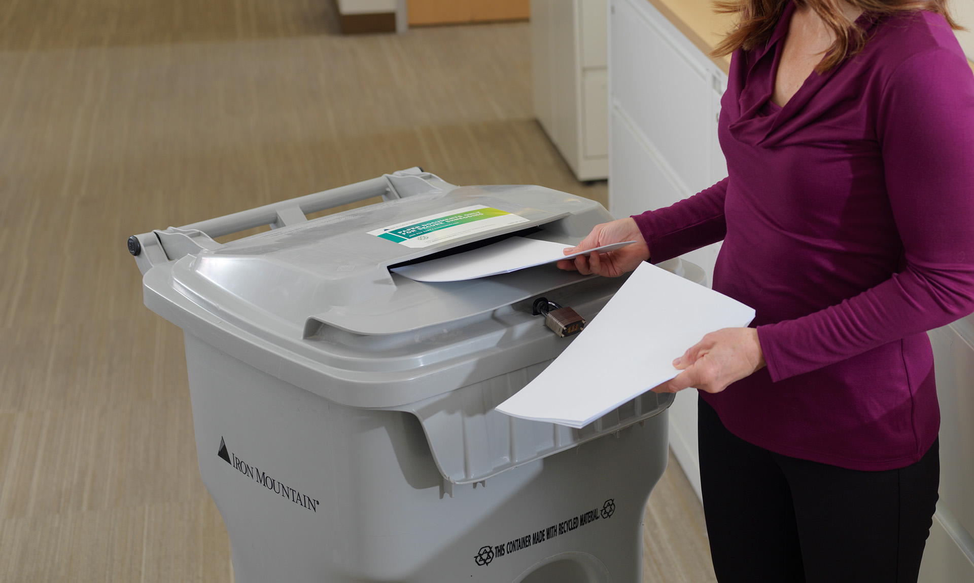 employee placing papers into IM shredding bin