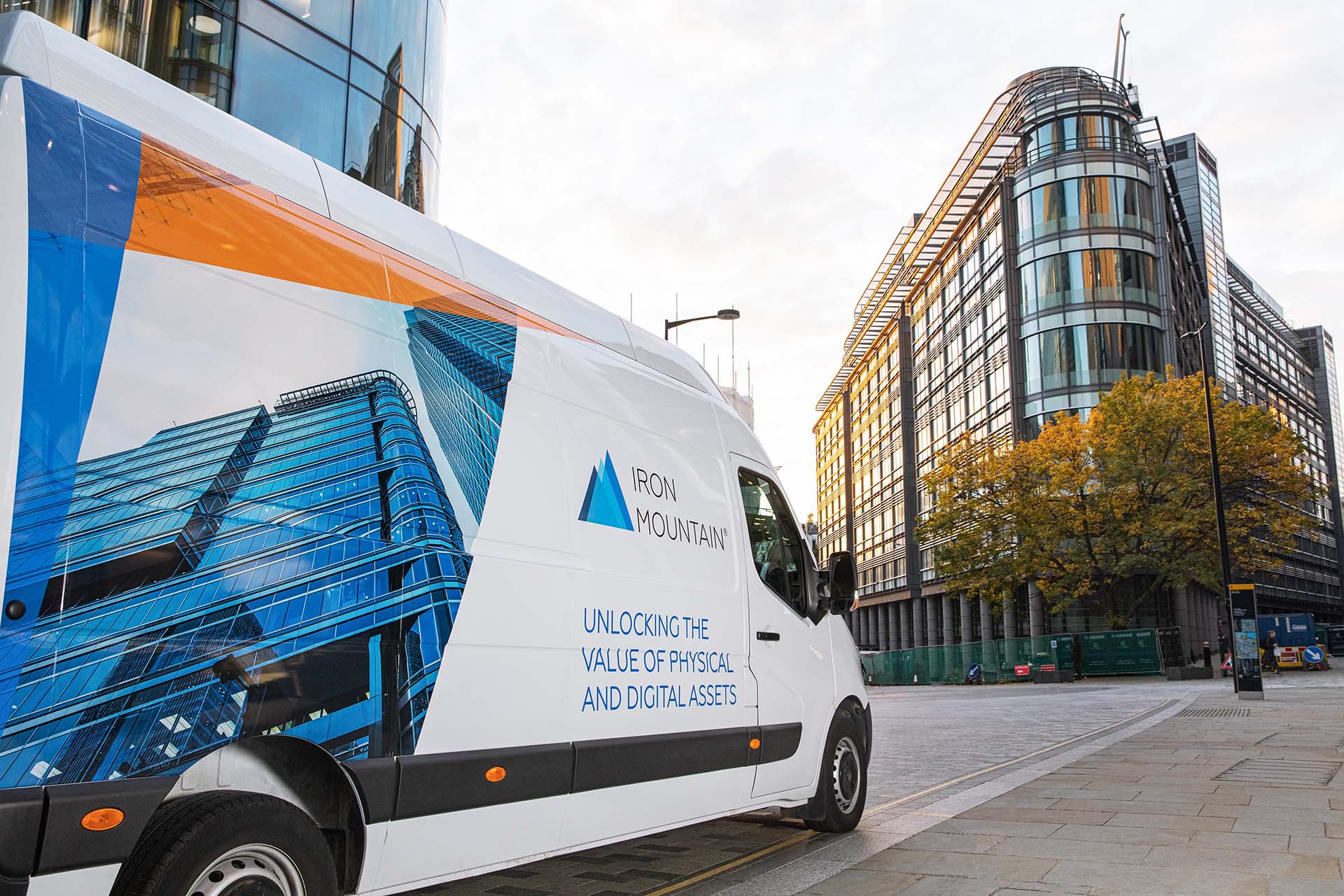 an Iron Mountain van parked next to sidewalk, with modern city backdrop