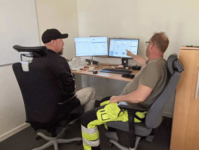 Two people are reviewing data on computer screens in an office.