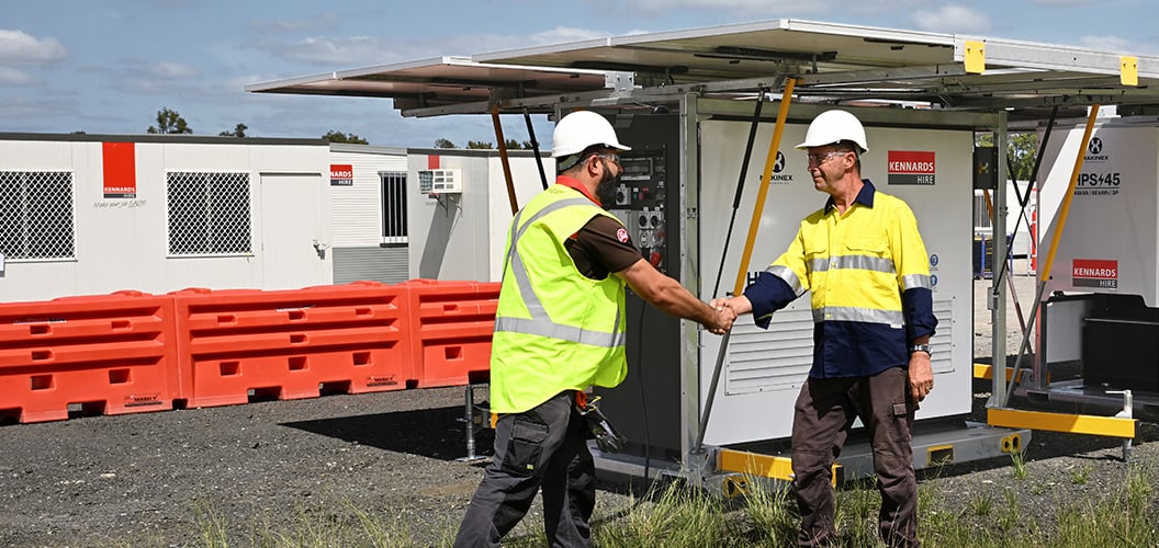 Two people shaking hands in front of a hybrid solar generator