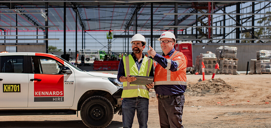 A Kennards Hire team member speaking to a project manager on a large construction site