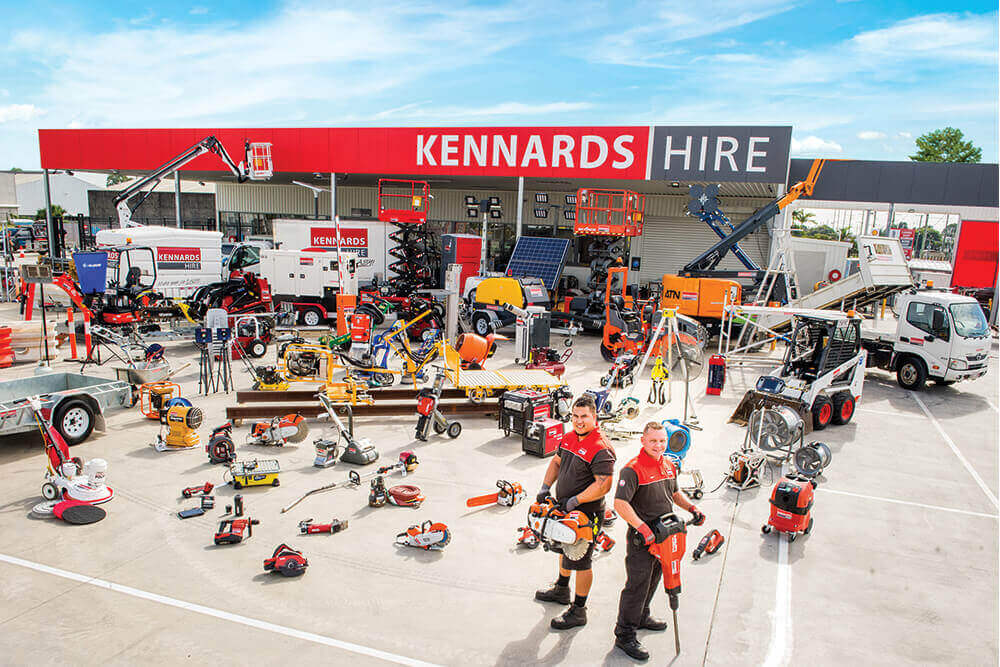 A birds eye view of a Kennards Hire branch - a large range of equipment spread out with two Kennards Hire team members standing in front