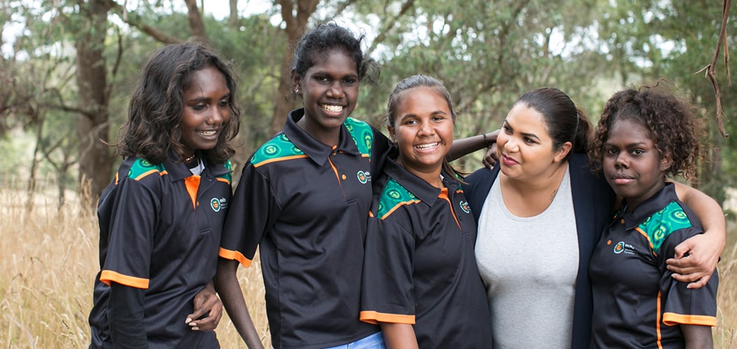 a group shot of teenagers and a mentor with arms over each others shoulders