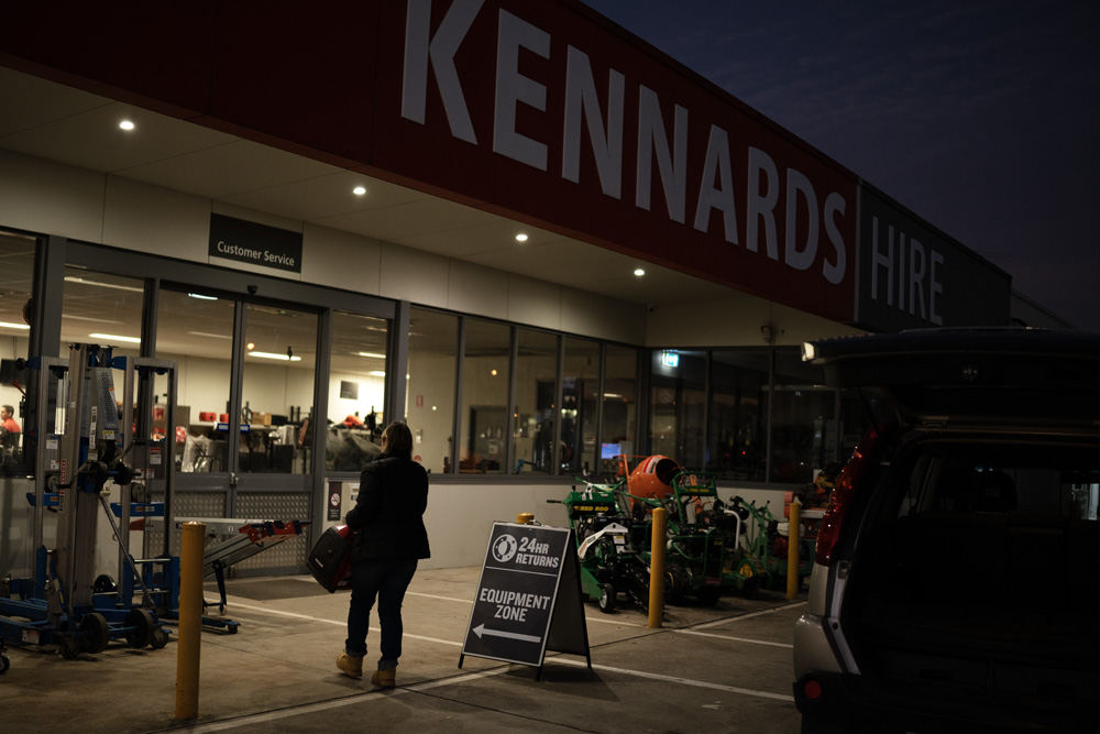 person walking into a Kennards Hire branch at night