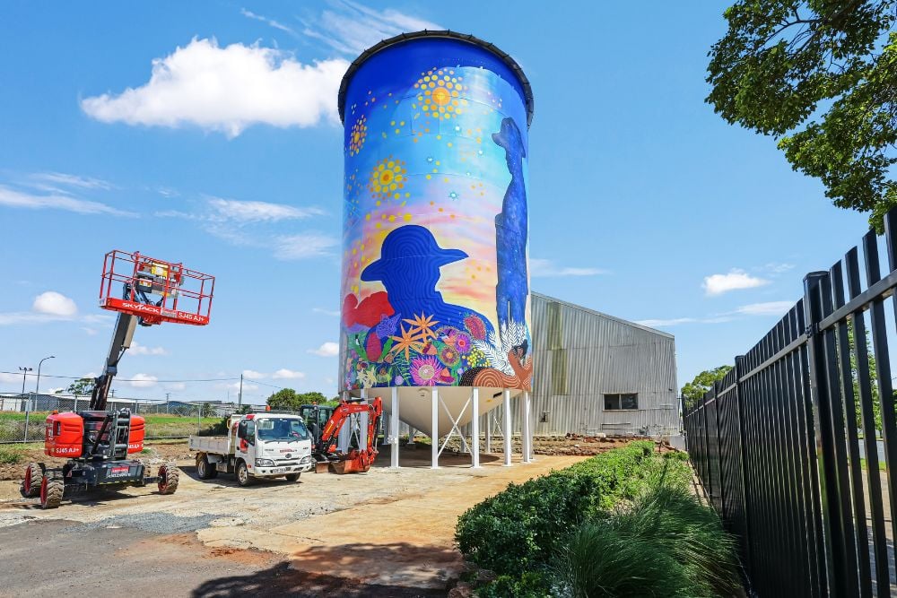 A zoomed out image of a boom lift and the silo that has a new painting