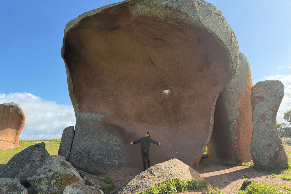 Kennards Hire Matt Jenkins standing under a big rock with his arms open