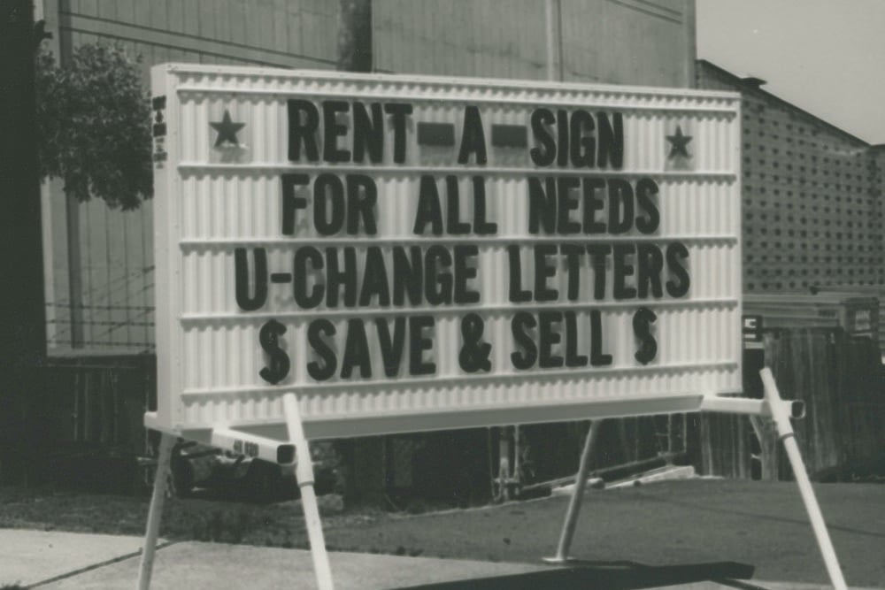 A black and white image of an old letter block sign that says "Rent a sign for all needs. U-Change letters. $ Save & sell $