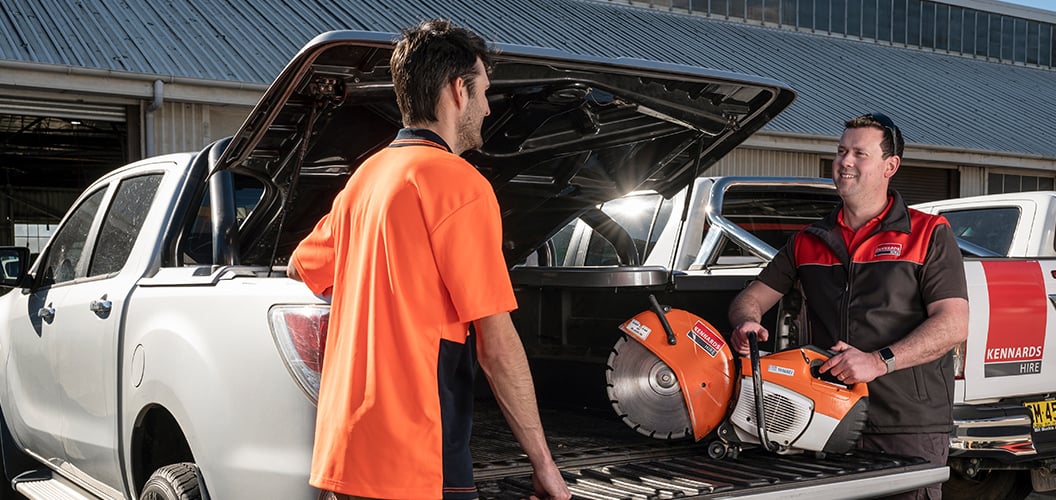 A Kennards Hire team member loading a demo saw into the back of a trade customers ute