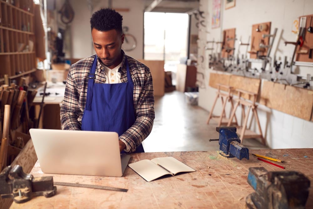 Tradesman working on a laptop in a workshop