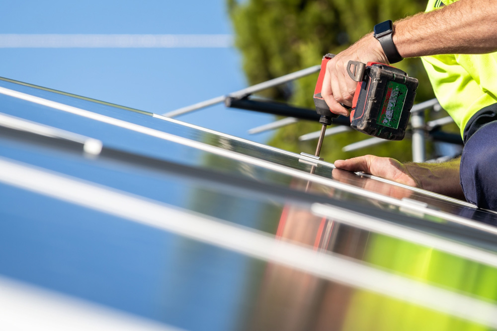 Tradesman installing solar panels on a roof
