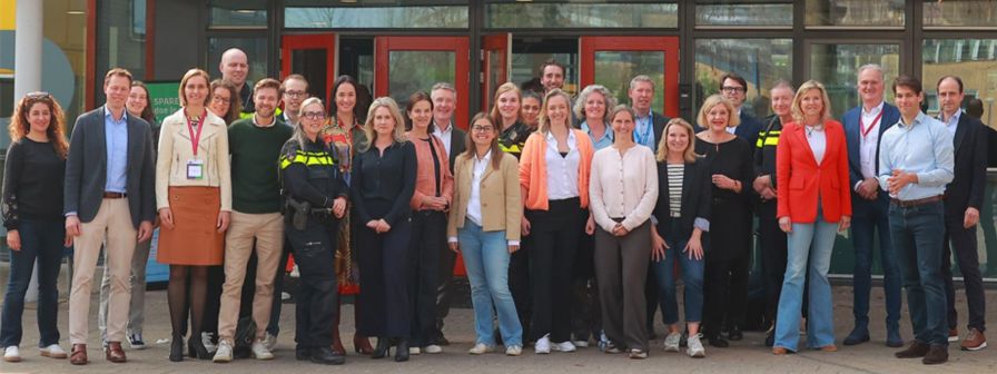 Groepsfoto met Faten (links), andere bankmedewerkers en politie bij de opening van Bank voor de Klas.