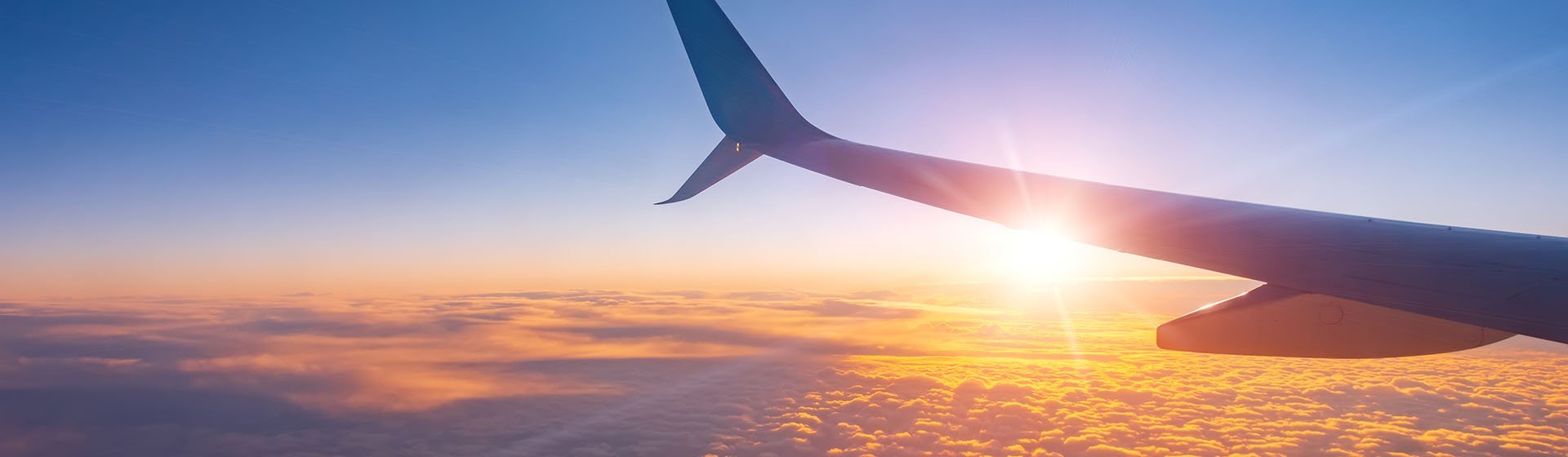 Lewis Silkin An aeroplane wing with the sun peaking from behind it whilst the plane is flying