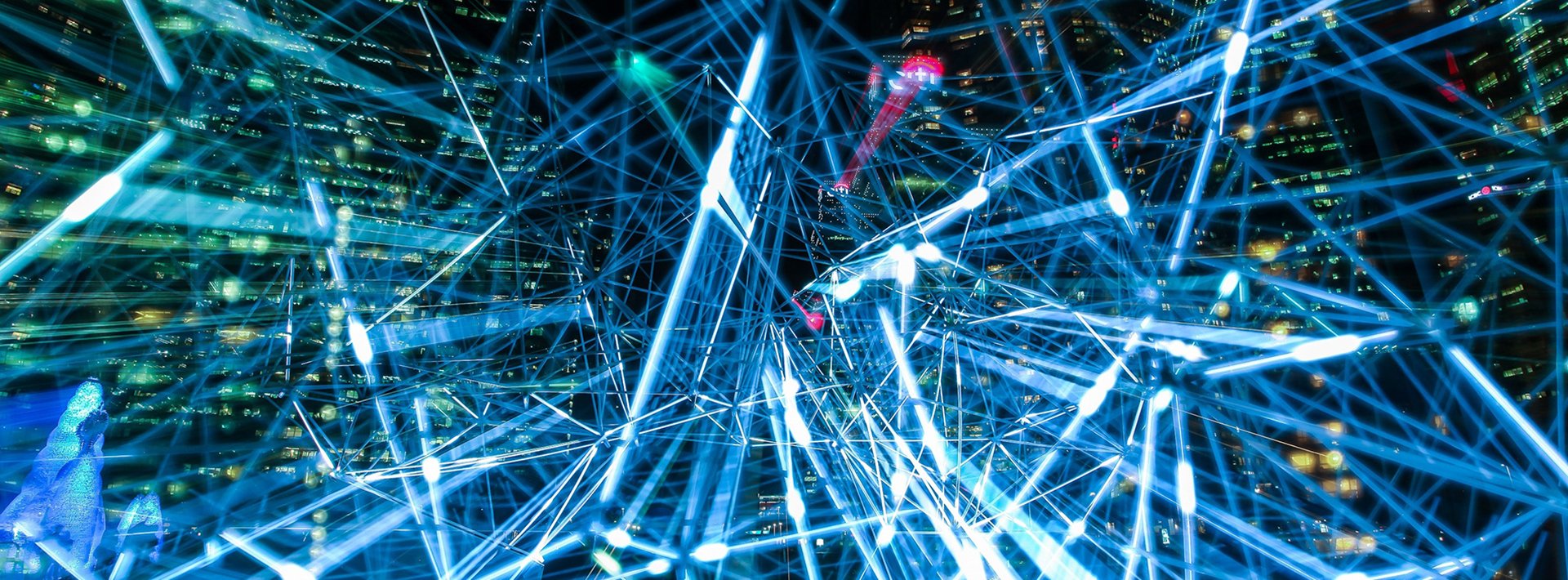 Lewis Silkin Vista of city buildings at night overlaid with a network pattern of nodes and lines of connecting blue light