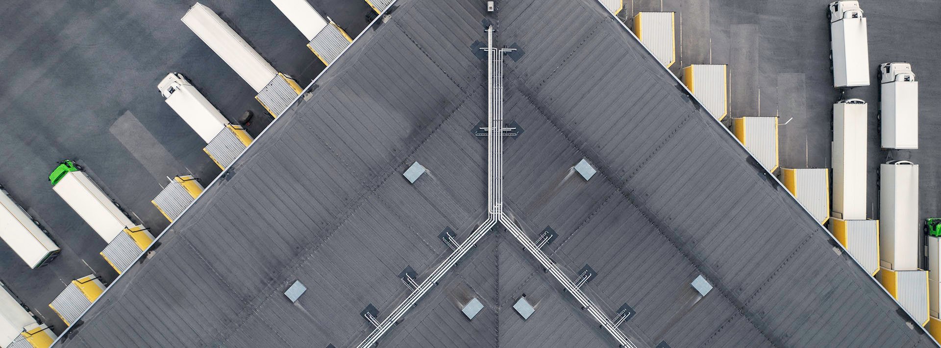Lewis Silkin Aerial view of a distribution centre with a grey roof, parked in the depot bays are green and white lorries