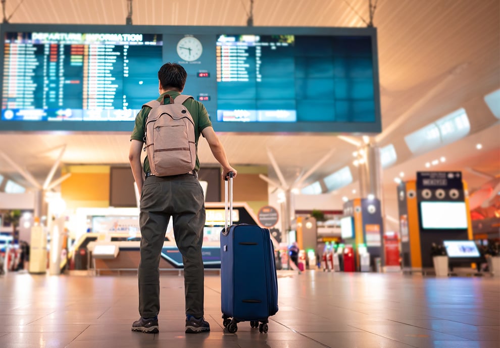 Lewis Silkin Person at an airport with their luggage looking at departures information.