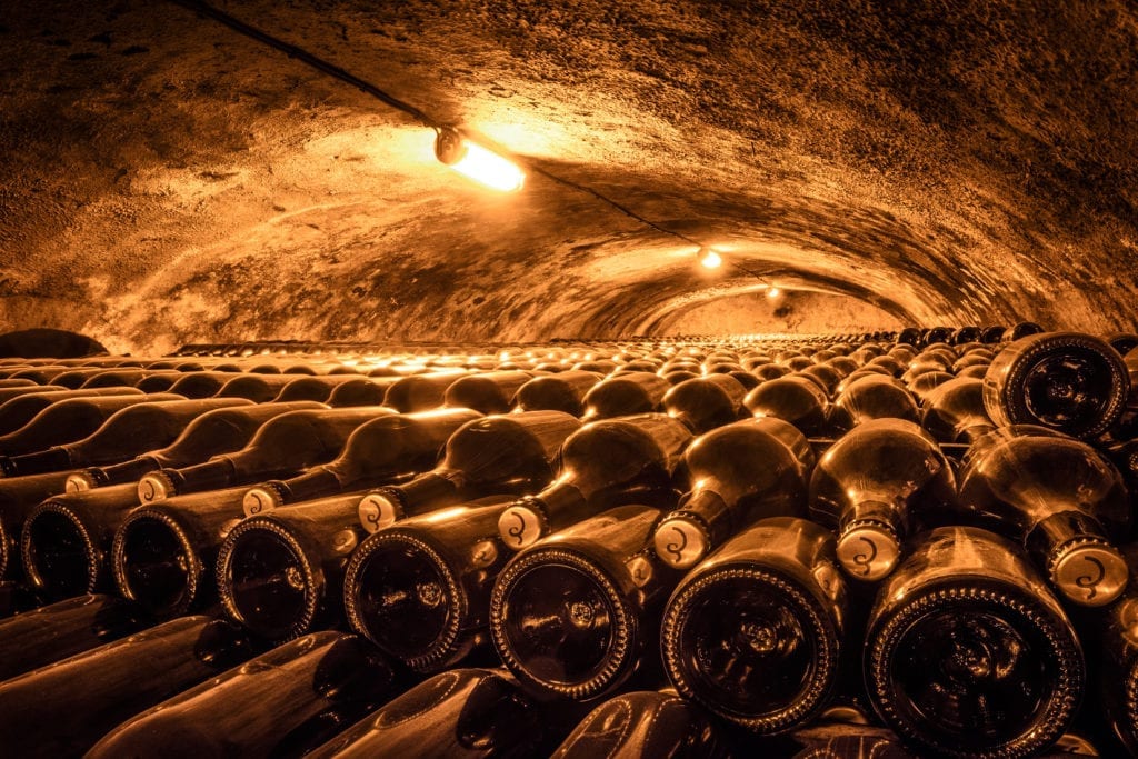 Rows of Champagne bottles in a dark cellar.