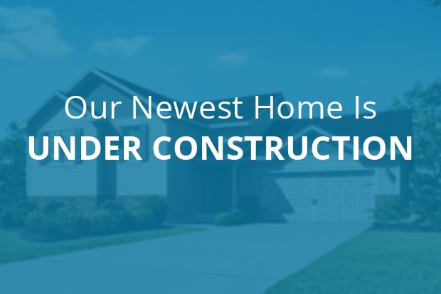 Our Newest Home is Under Construction text overlaid on out-of-focus home image