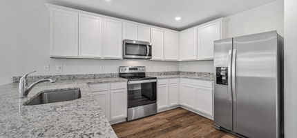 Spacious kitchen with white cabinetry and granite counters