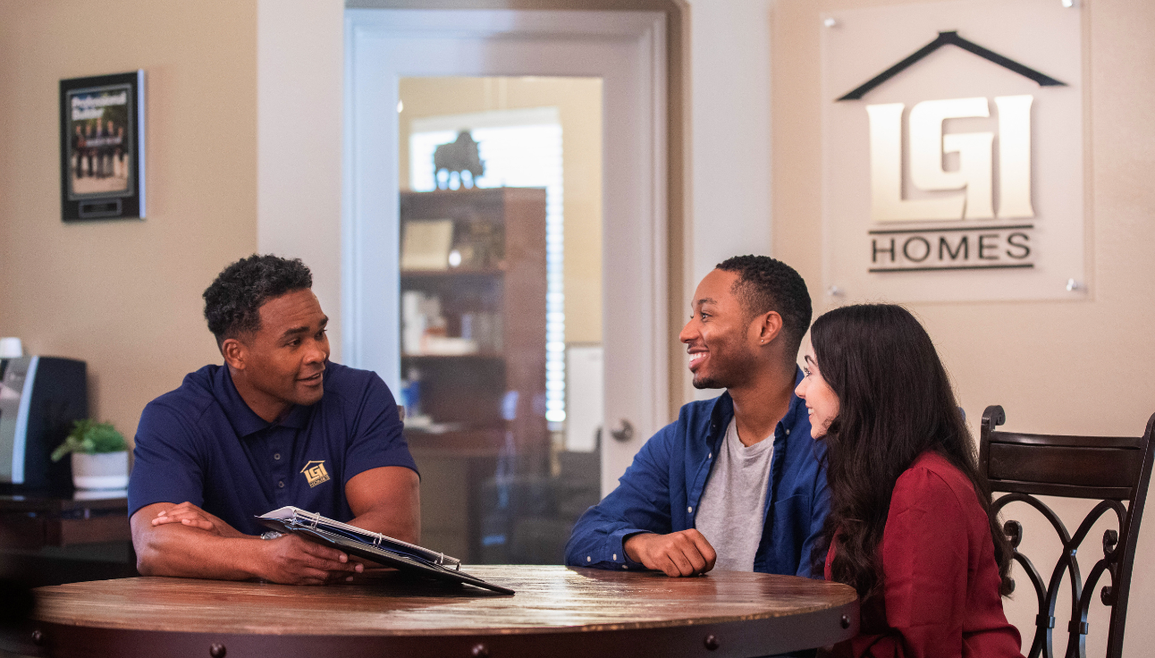 Couple sitting at table with New Home Consultant discussing the steps to buying
