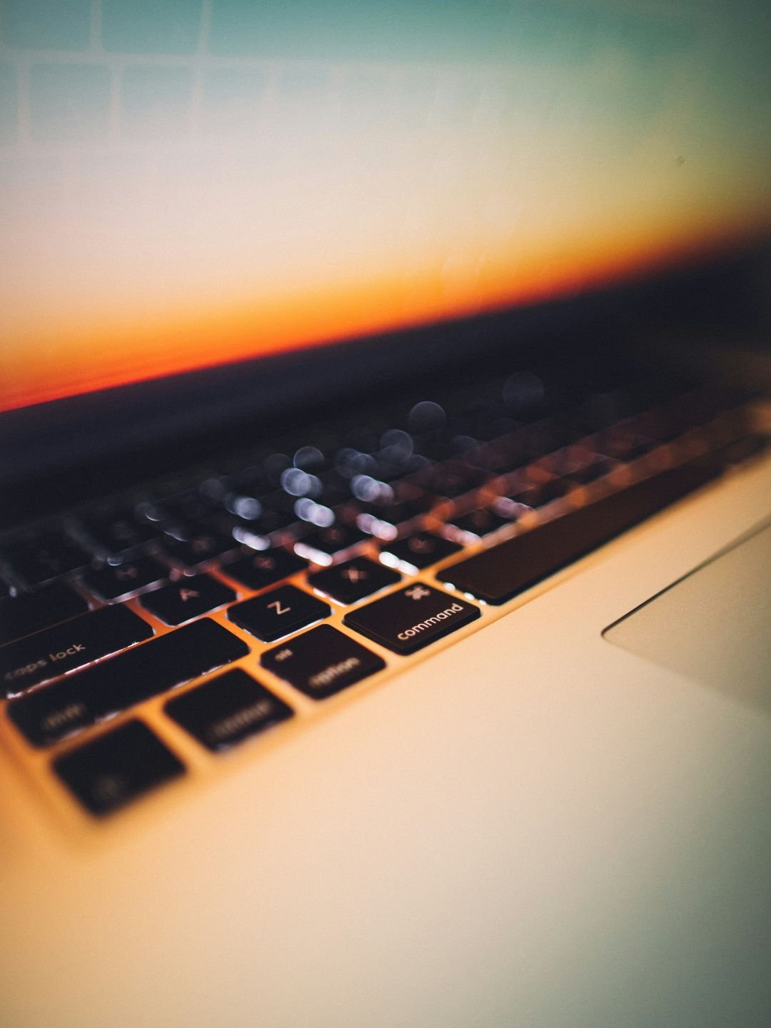 Close up of laptop keyboard lit up by screen light in warm sepia lighting
