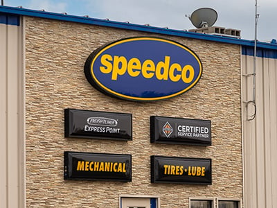 A photo of the exterior of a Speedco repair shop with various mechanical signs on the front